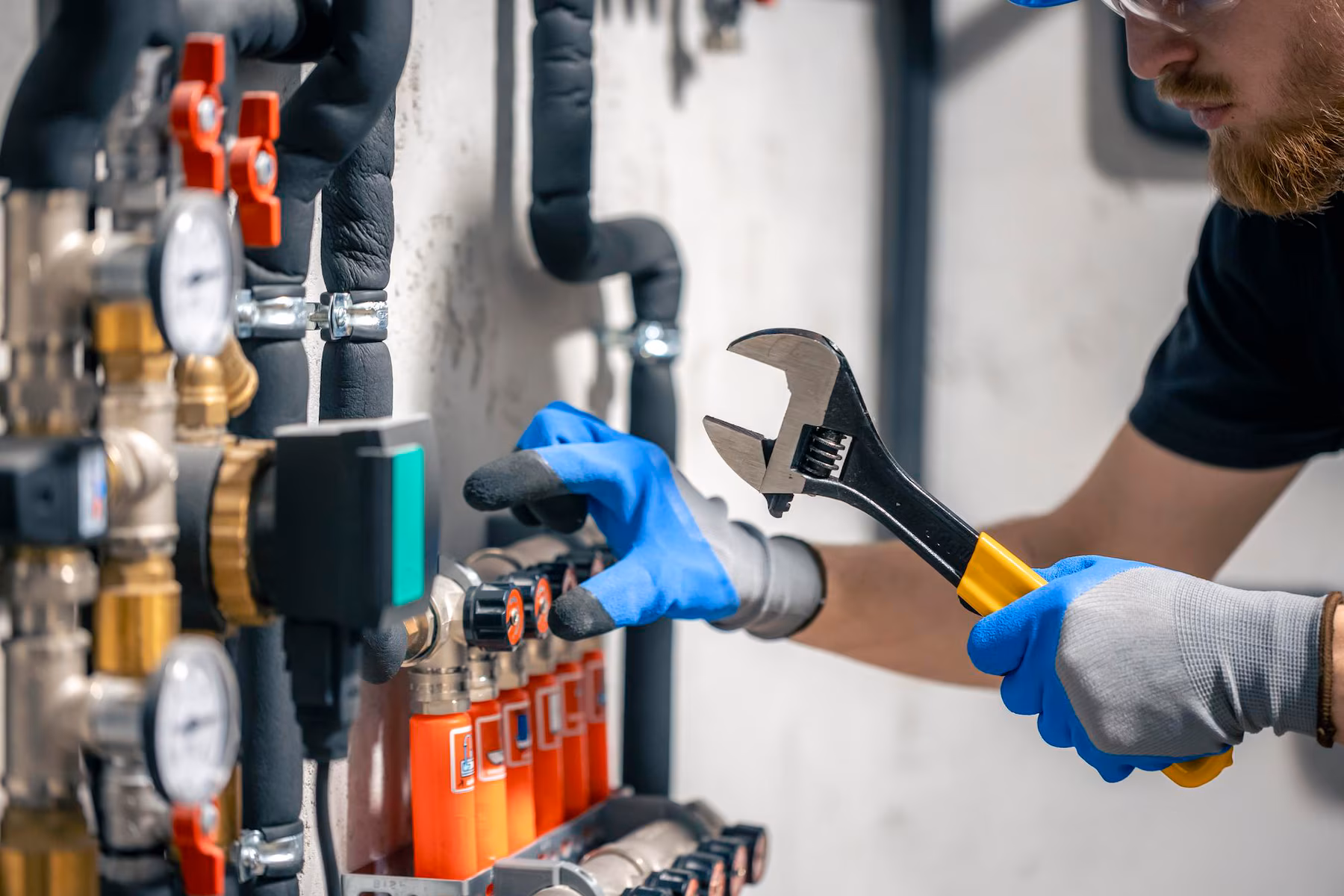 man-installs-heating-system-house-checks-pipes-with-wrench_169016-52877